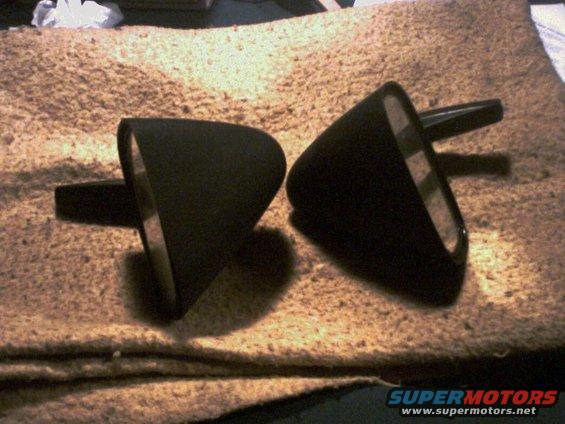 Two black side mirrors with triangular housings sit on a textured surface