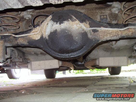 Underside view of a vehicle's rear differential and suspension with visible oil leaks