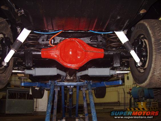 Underside of a vehicle showing the rear axle, shocks, springs, and exhaust system