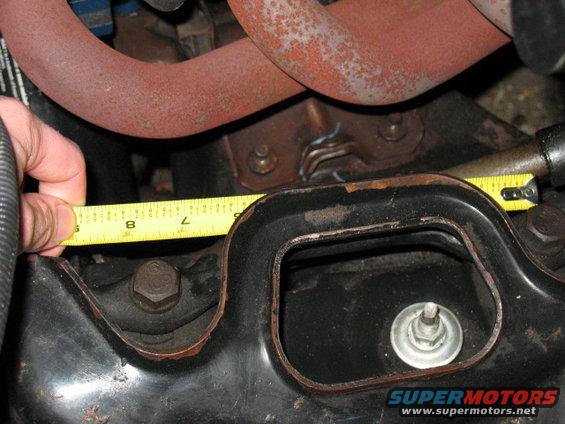 hand holding tape measure to engine component