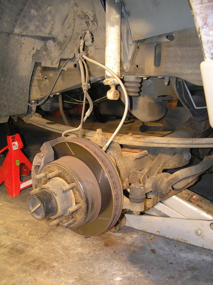 p1200057.jpg Now it's time to lower your floor jack. Keep lowering it until the axle separates from the leaf spring. The leaf spring has a short stud that fits into a notch in the top of the axle. This should separate naturally by dropping the axle with the floor jack -- you may need to pry it apart with a large screw driver.