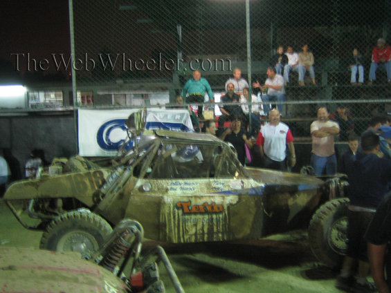 Mud-splattered off-road buggy with number 618, "Tuffin" logo, and spectators in background