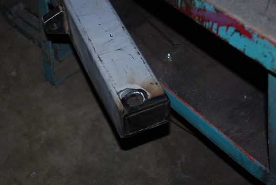 Close-up of a welded metal tube with a circular insert, resting on a workbench