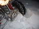 2005 Honda TRX 450 R - The front suspension and tire of a 2005 Honda TRX 450 R are visible, partially buried in snow during a winter run.