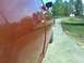 1979 Ford Ranchero - Side profile of a red vehicle, with a clear reflection of trees and sky on its polished surface.