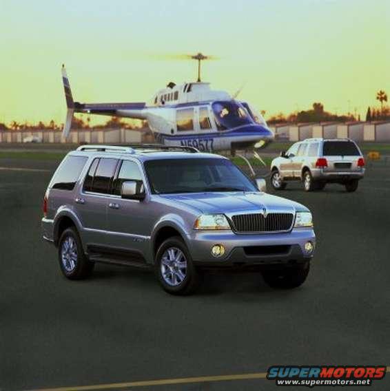 Silver SUV parked on asphalt with a helicopter behind it