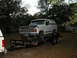 1986 Ford F-350 - A white Ford Bronco is loaded onto a trailer, with a portion of another vehicle visible to the left.
