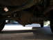 1986 Ford F-350 - Underside view of a truck's rear differential and exhaust system, with a car in the background.