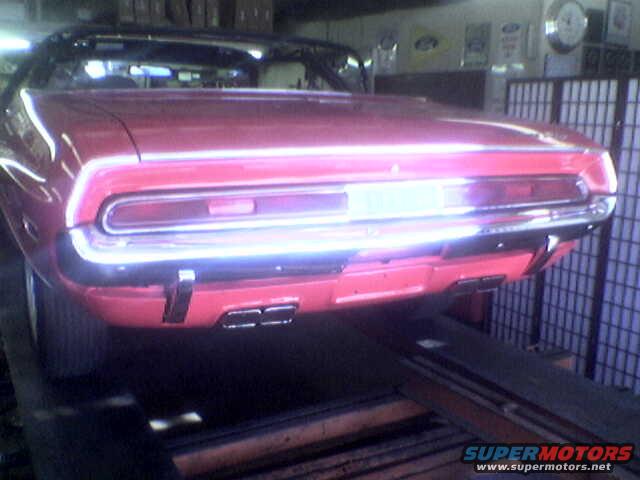 Red convertible car rear view on a lift, chrome bumper, dual exhaust pipes