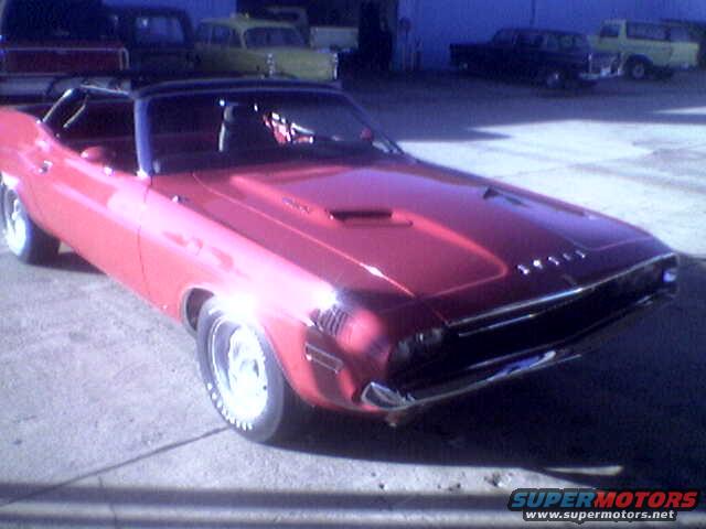 Red convertible muscle car, 3q front view. Other vehicles in background