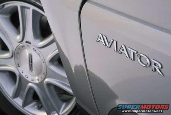 Close-up of 'AVIATOR' emblem on a silver vehicle, with a Lincoln wheel visible