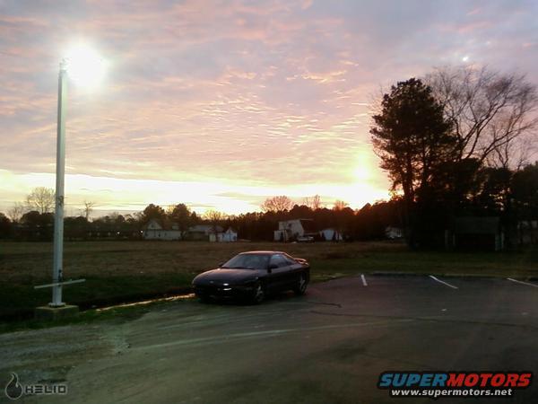 Black 1993 Ford Probe parked in a field at sunset