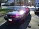 2003 Mercury Marauder - A dark sedan, possibly a police car, is parked in a driveway with a pickup truck beside it.