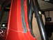 1979 Ford Bronco - Detail shot of the interior door jamb and roll bar structure of a red vehicle.