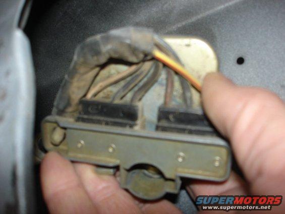 Close-up of a gray electrical connector with wires, held by a hand
