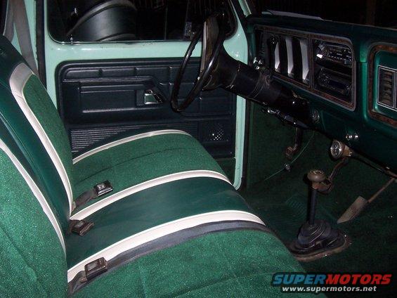 Green striped bench seat and dashboard of an older truck. Floor shifter visible