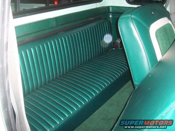 Green vinyl bench seat with vertical pleats and a white stripe on the side of the passenger seat