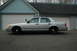 2003 Ford Crown Victoria - Side view of a silver 2003 Ford Crown Victoria sedan, equipped with police lights, parked in front of a residential garage.