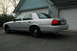 2003 Ford Crown Victoria - Rear view of a silver 2003 Ford Crown Victoria police car parked in front of a garage.