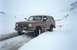 1989 Ford Bronco - A brown 1989 Ford Bronco navigates a snowy road, demonstrating its off-road capability in winter conditions.