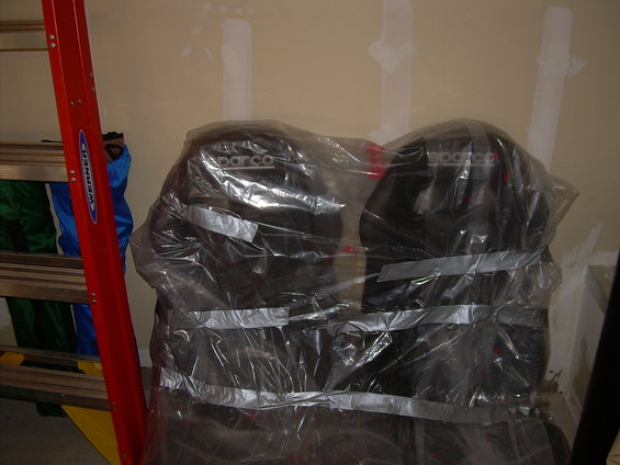 Two black Sparco car seats covered in plastic wrap and duct tape