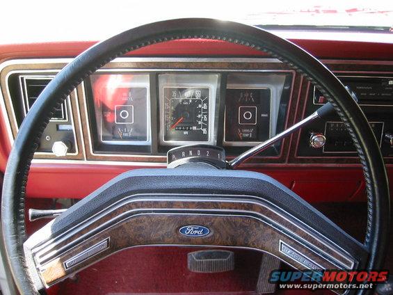 1978 Ford Bronco XLT dashboard with wood grain trim, red interior, and a Ford logo on the steering wheel