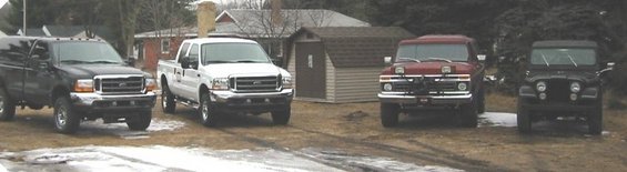 four trucks and a jeep parked outside