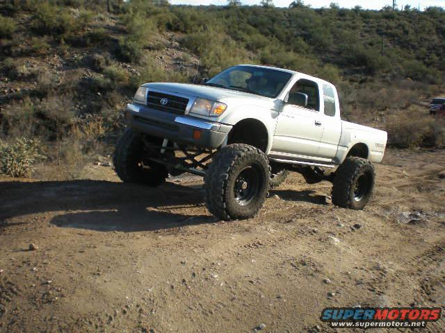 lifted Toyota Tacoma pickup truck on dirt road, another vehicle in background