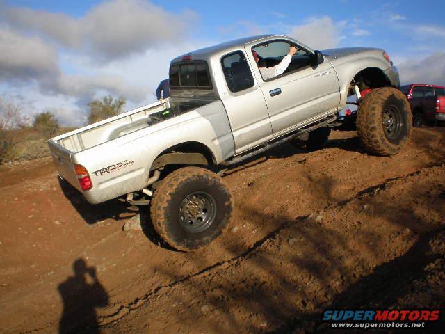 Silver pickup truck with large tires on a dirt hill