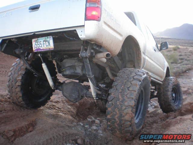 rear view of lifted pickup truck with large tires on dirt terrain
