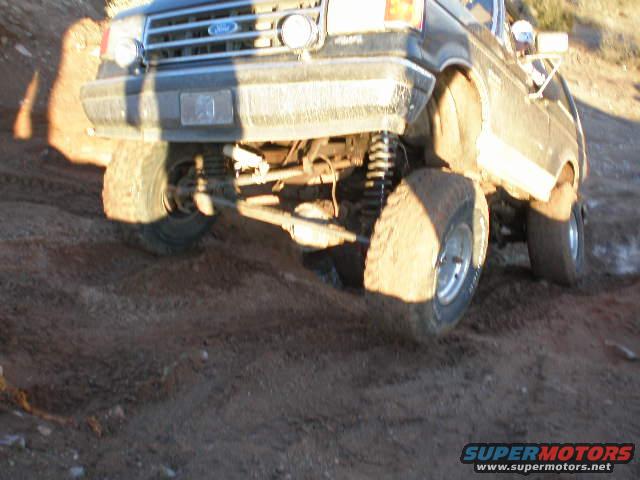 Front driver's side of a lifted 1991 Ford Bronco off-roading on a dirt trail