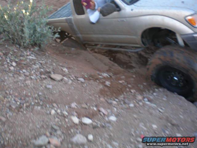 Truck stuck in a ditch on a dirt trail, with one wheel off the ground