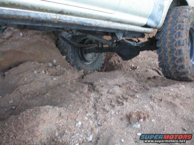 Off-road vehicle's rear axle and tire stuck in dirt