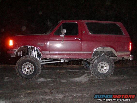 Red 1991 Ford Bronco side view, lifted with large tires