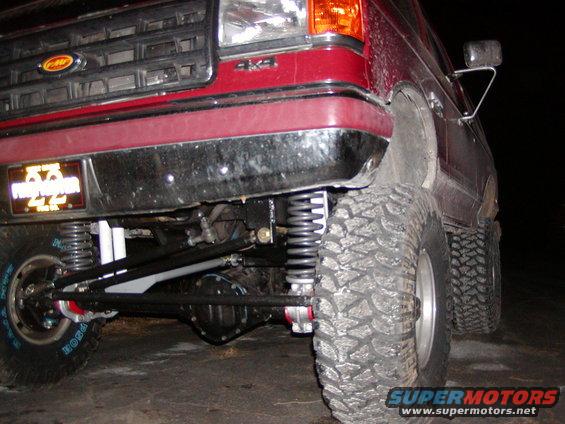 1991 Ford Bronco front suspension with large tires and lifted body. Red paint visible