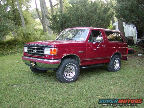 Red 1992 Ford Bronco parked on grass, front 3/4 view. Chrome bumper and wheels visible