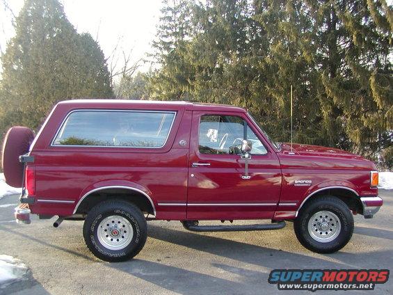 Red 1991 Ford Bronco side view with spare tire on rear