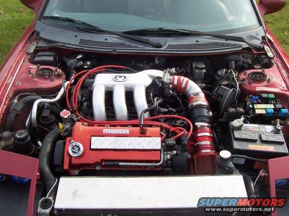 Engine bay of a red car with a Mazda engine. Intake is red and silver