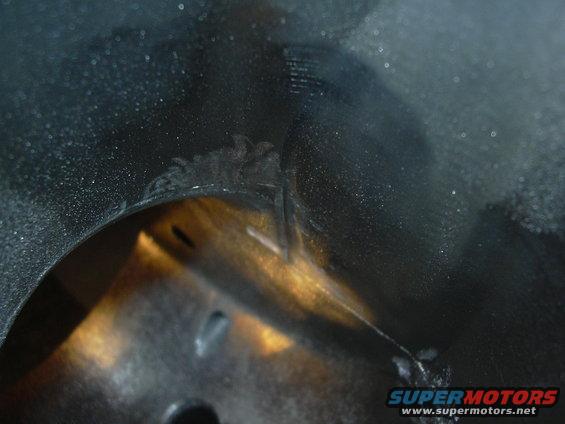 Close-up of engine bay part with Supermotors.net watermark