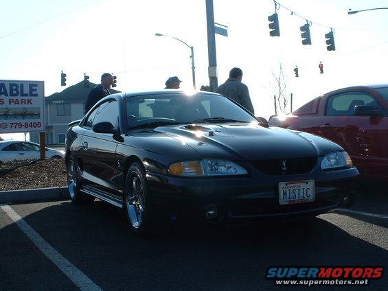 Black Ford Mustang with 'MISTIC' license plate, parked outdoors
