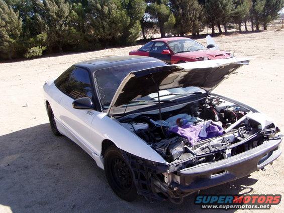 White 1993 Ford Probe with black roof, hood open, and front bumper removed