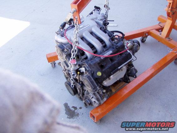 Mazda engine being held by an orange engine stand, chains attached