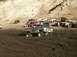 1978 Ford Bronco - Several off-road vehicles are gathered in a muddy area, with one truck prominently stuck in the foreground.