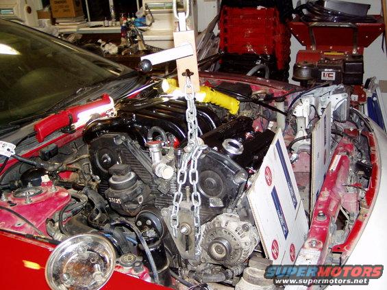 Red car engine bay with engine hoist and chains suspending the engine