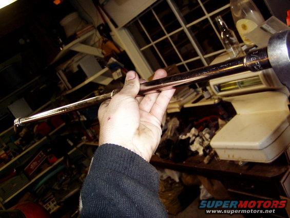 Hand holding a metal rod with a socket attached