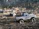 1978 Ford Bronco - A group of people and several off-road vehicles are gathered in a muddy area, with one truck stuck in the mire.