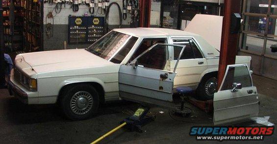 1991 Ford Crown Victoria LTD with doors removed, on a lift in a garage
