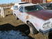 1973 Ford Ranchero - A weathered pickup truck with a camper shell sits in a dry, grassy field next to a wooden fence.