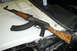 1968 Ford Mustang - An AK-47 rifle is placed on the hood of a car, with visible rust and repair work on the vehicle's body.