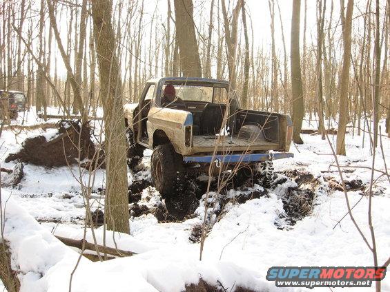 Modified off-road truck stuck in mud and snow, another SUV visible in background